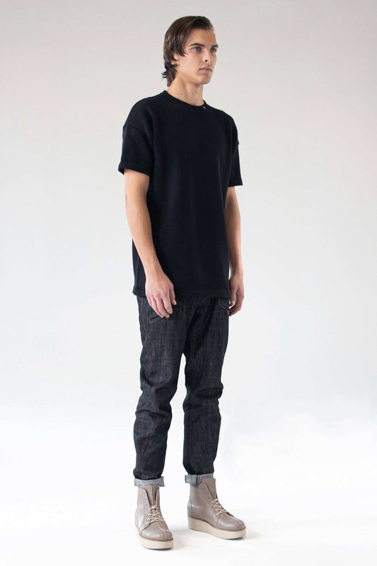 Front view of model wearing the One Wolf Knitted T-Shirt SEEKER in black, 100% cotton, unisex minimalist design