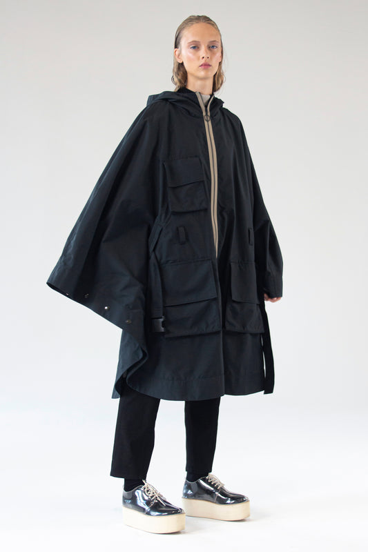 Model wearing One Wolf Poncho SEEKER in black, side view, waterproof cotton outerwear.