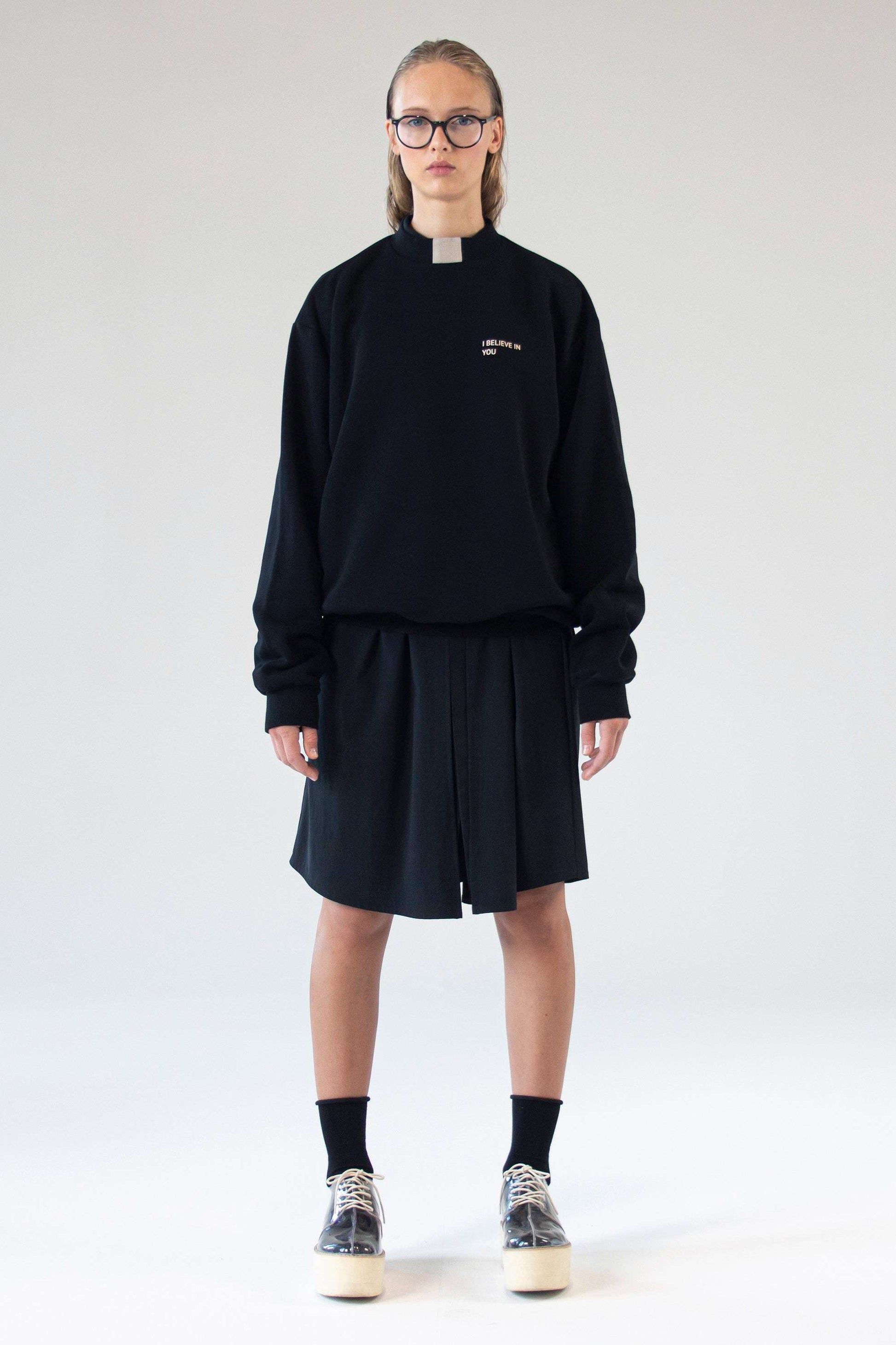 Unisex black sweater ‘I Believe In You’ by One Wolf, front view on model with relaxed fit and subtle silk print text.